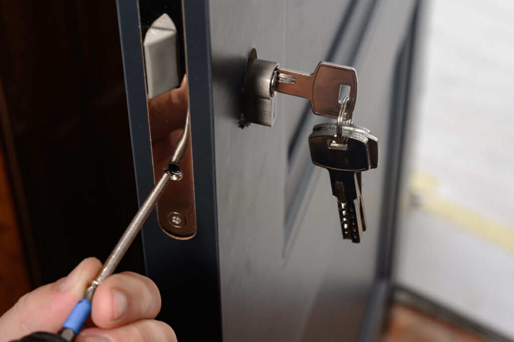 A locksmith installs a lock and handle on a home’s door, with keys attached.