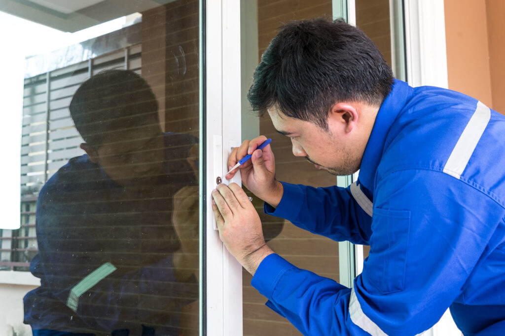 Tech repairing sliding door lock with tools during residential locksmith service.